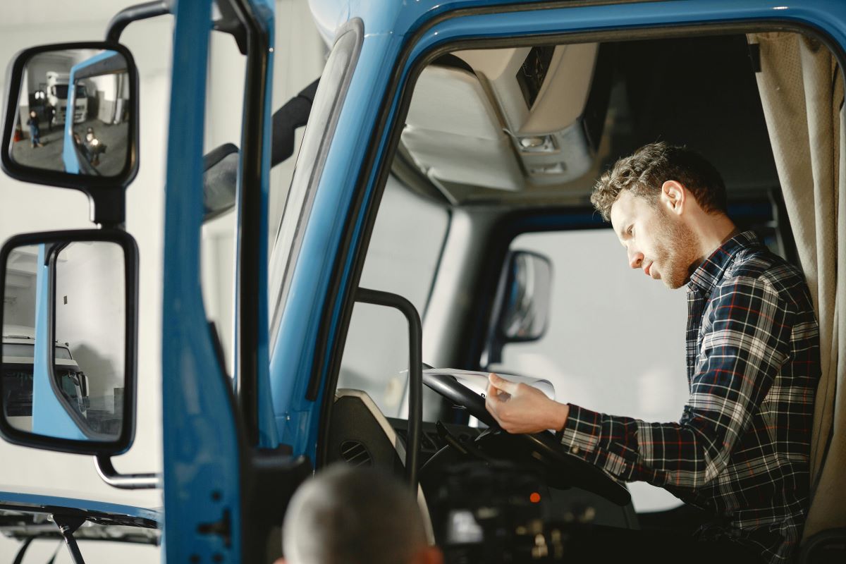 image of a man sitting in a lorry looking down at a bit of paper