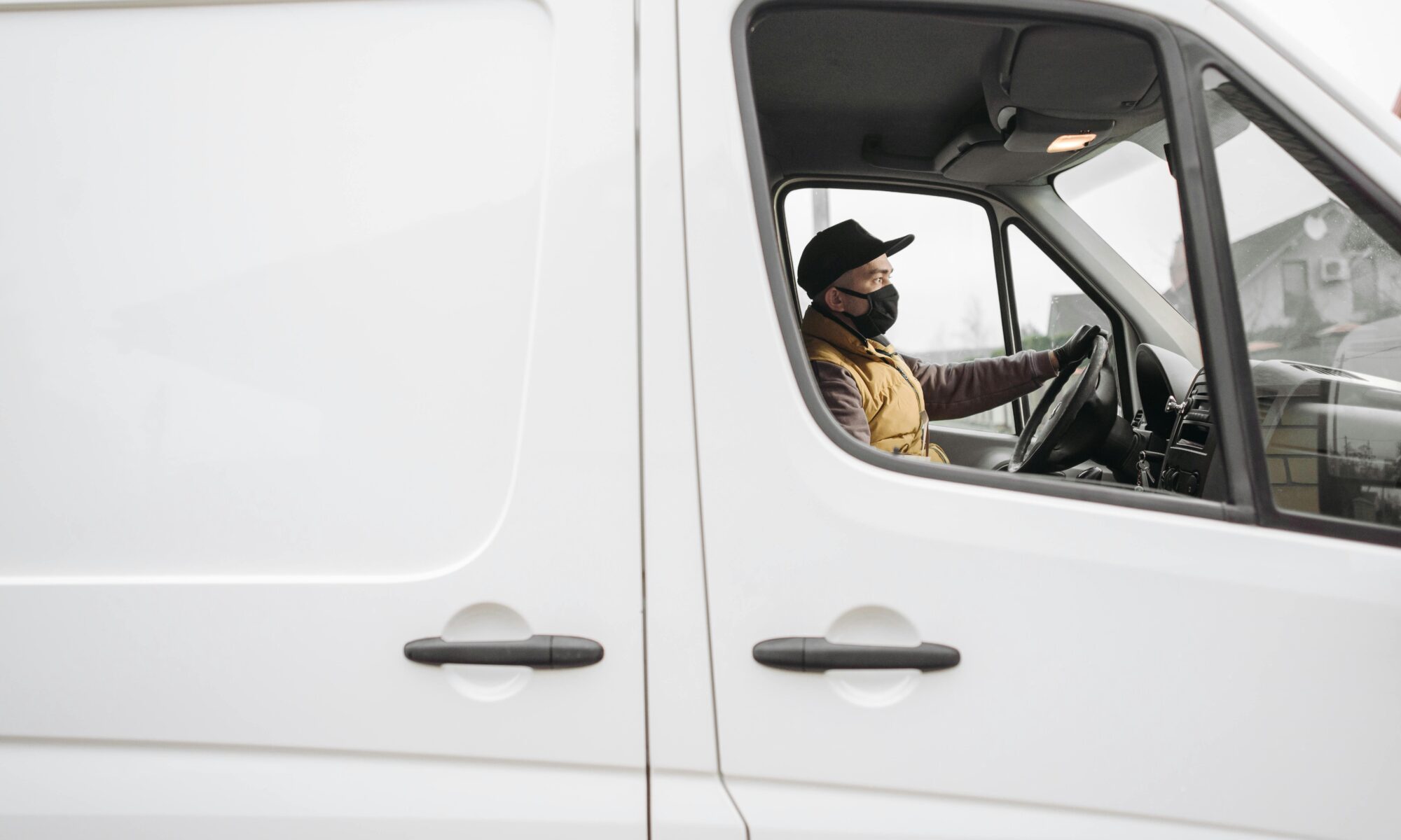 man in a white van wearing a mask driving
