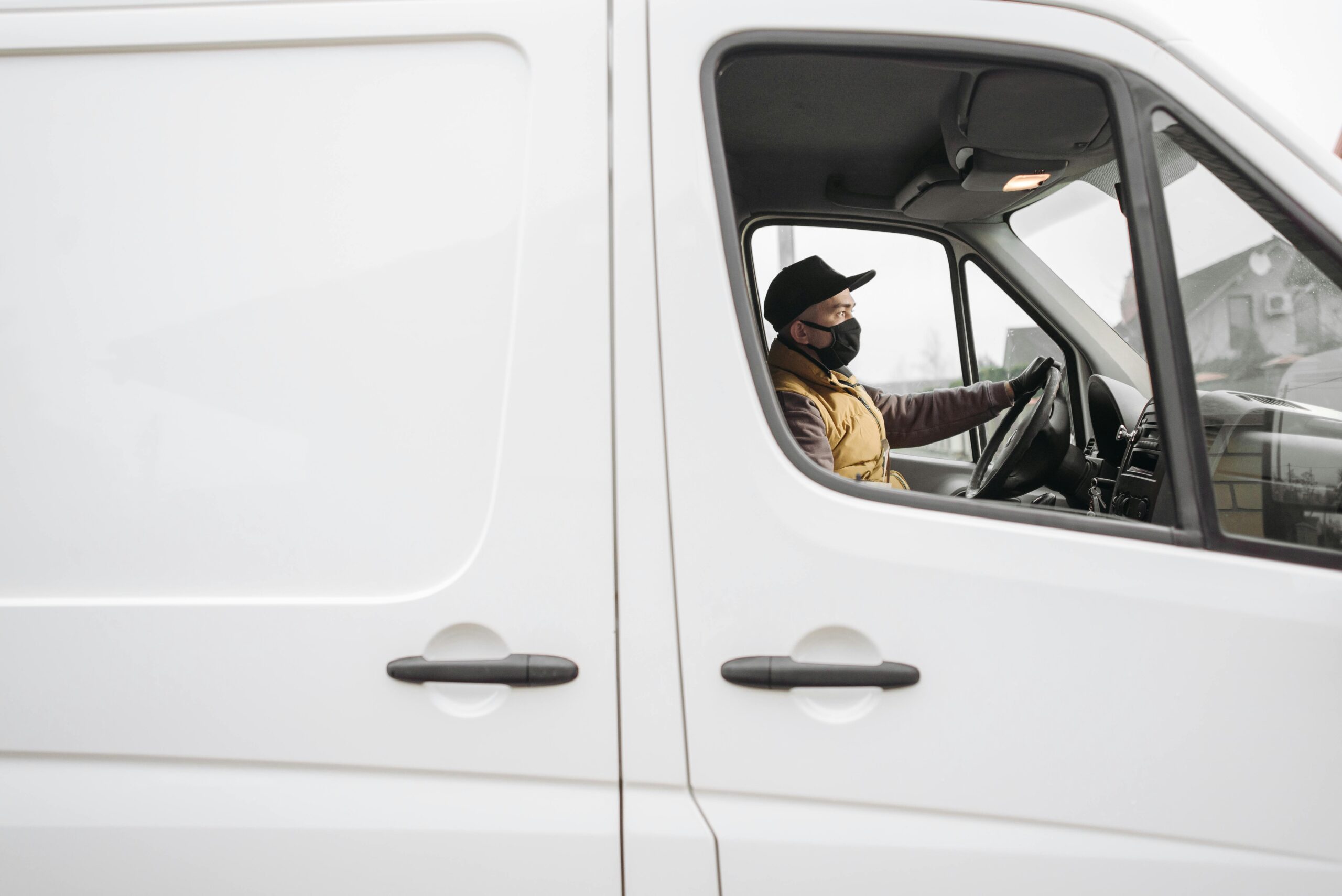 man in a white van wearing a mask driving